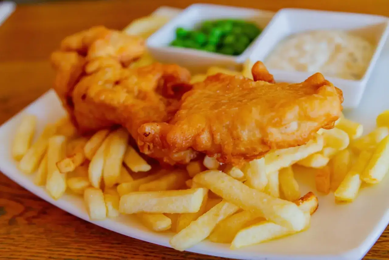 Fish and chips, un classico da provare per capire cosa mangiare a Londra. Servito con piselli e salsa tartara.