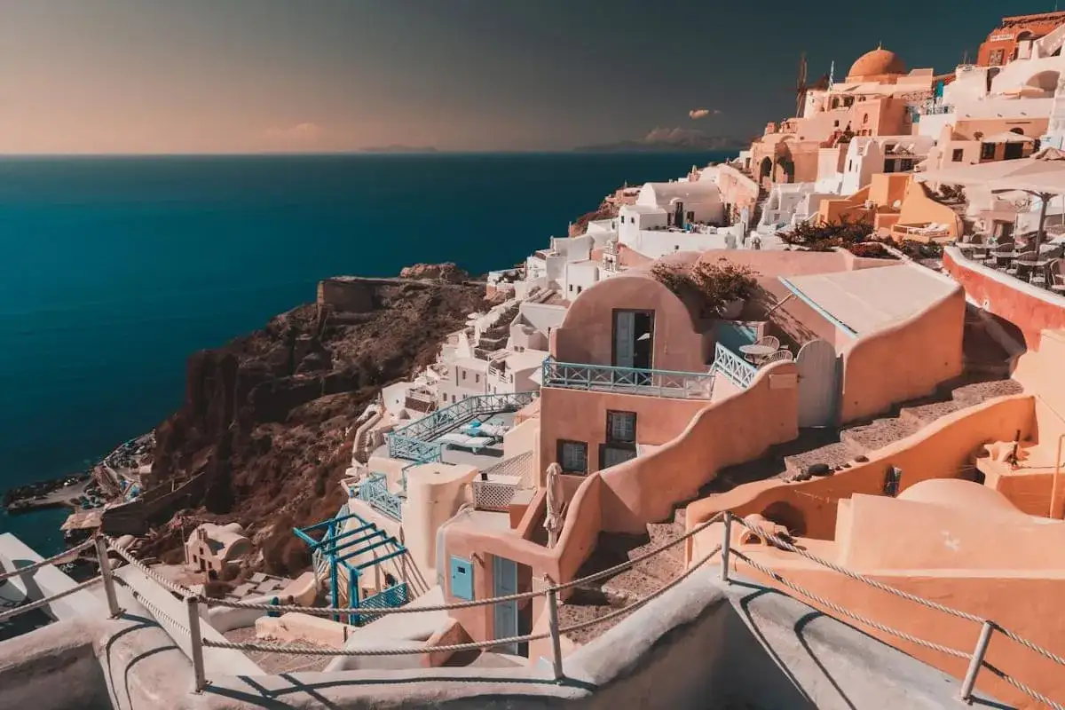 Case bianche e blu aggrappate alla scogliera a Santorini, un sogno per chi cerca cosa fare a Santorini in 7 giorni.