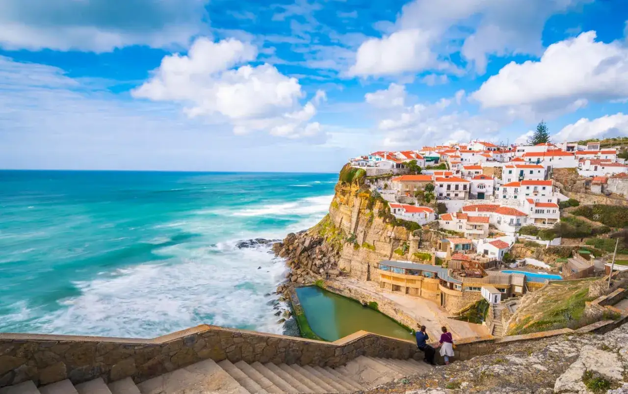 Villaggio costiero con case bianche e tetti arancioni, ideale per chi cerca dove andare a vivere all'estero con pochi soldi. Mare turchese e scogliere.
