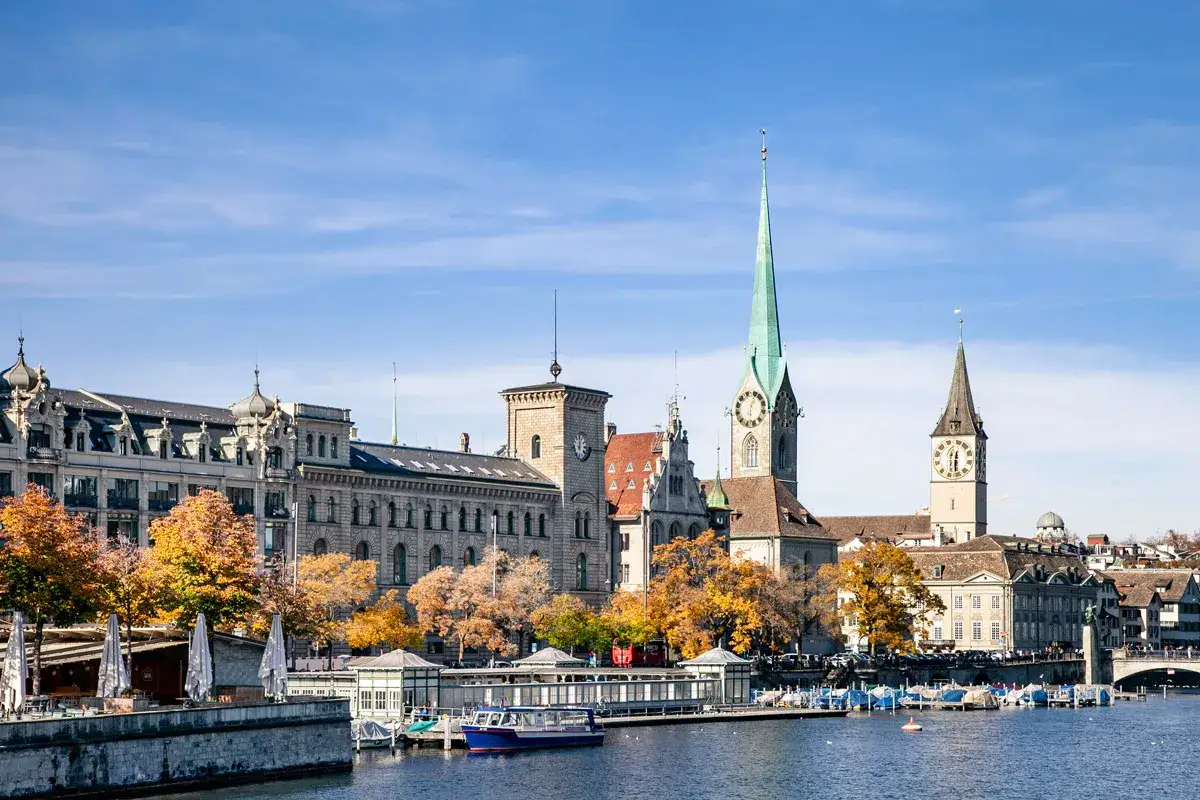 Un'idea di cosa vedere a Zurigo in un giorno: il fiume Limmat con le sue chiese storiche, edifici eleganti e alberi autunnali.