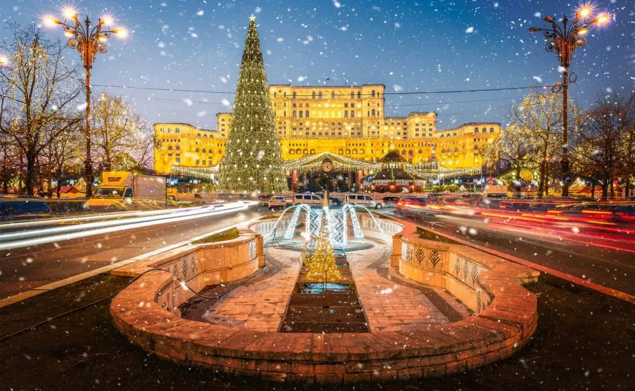 Un maestoso albero di Natale illumina Bucarest a dicembre, con il Palazzo del Parlamento sullo sfondo e una fontana scintillante.