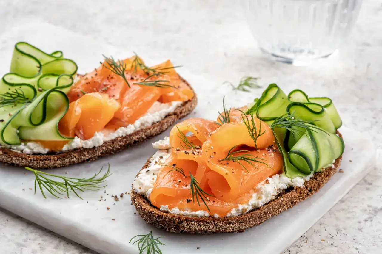 Sm&oslash;rrebr&oslash;d con salmone affumicato, cetrioli e formaggio cremoso. Un'idea su cosa mangiare a Copenaghen per un pranzo leggero e gustoso.