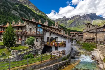 Un incantevole borgo da visitare in Piemonte, con case in pietra, balconi fioriti e un torrente che scorre tra le montagne.