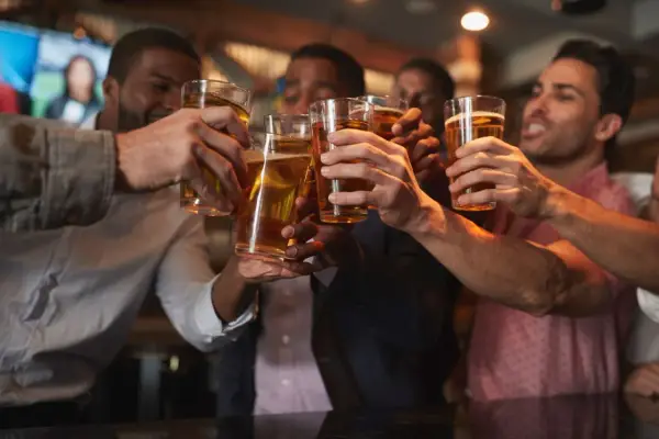 Amici brindano con birra in un locale, un brindisi per l'addio al celibato.