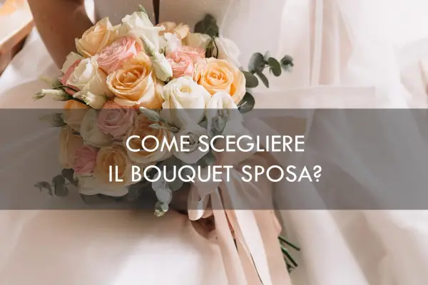 Un bouquet sposa elegantissimo con rose pesca, rosa e bianche, tenuto da una sposa.