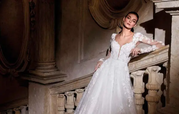 Modella con abiti da sposa per sembrare più alte, posa su una scala di pietra antica.