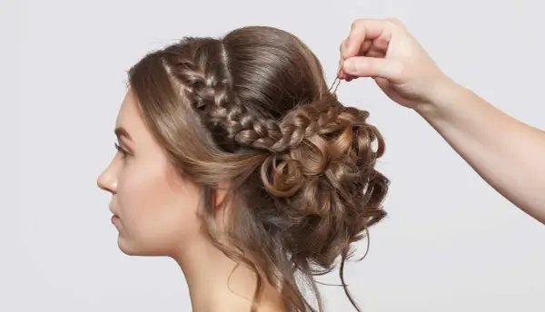 Treccia semiraccolto, un'acconciatura sposa elegante con ricci morbidi e una mano che aggiunge un fermaglio.