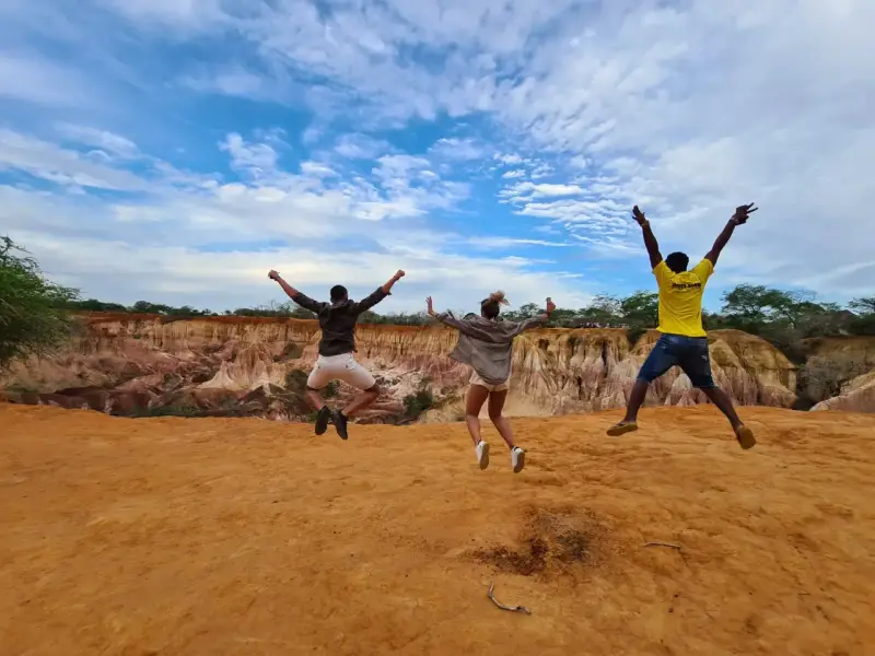 Tre amici saltano felici in Kenya, un'esperienza indimenticabile che vale ogni euro del costo safari Kenya.