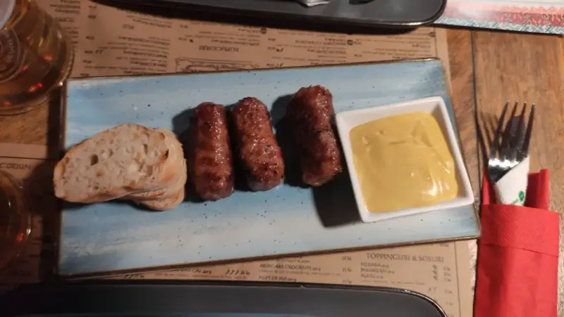 Mici e pane: un assaggio di cosa mangiare a Bucarest. Salsicce grigliate servite con pane fresco e senape.