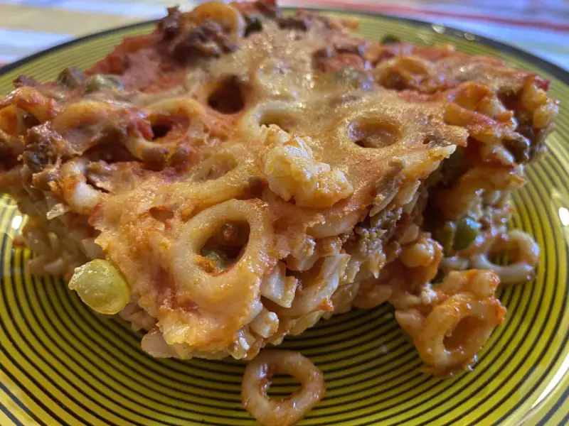 Un pezzo di pasta al forno con ragù e piselli, un'idea gustosa per cosa mangiare a Palermo.
