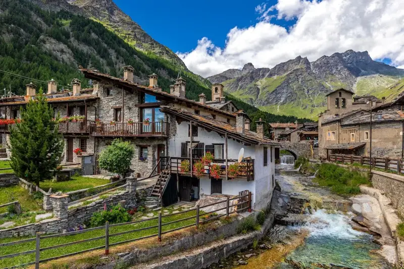 Un incantevole borgo da visitare in Piemonte, con case in pietra, balconi fioriti e un torrente che scorre tra le montagne.
